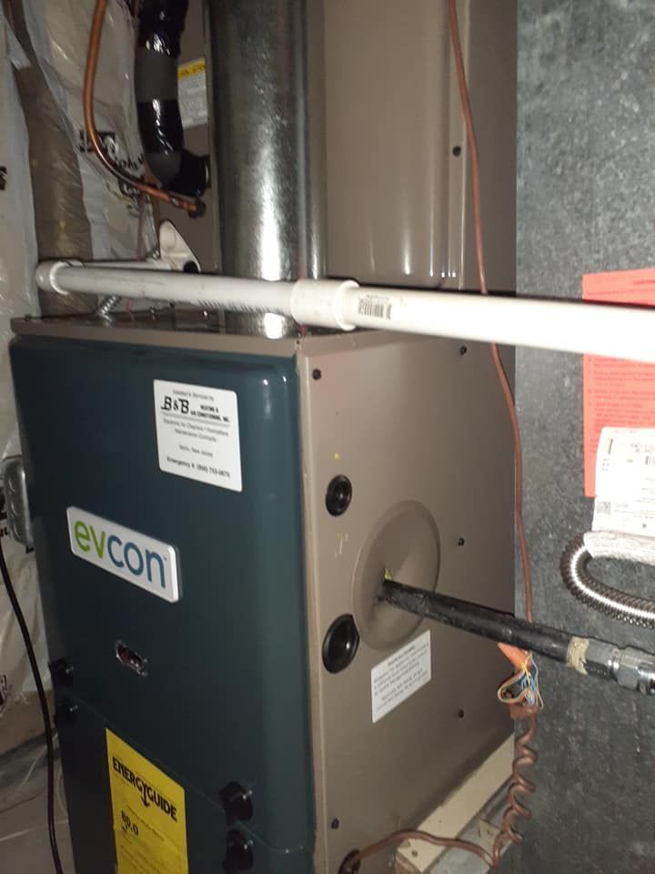Blue and beige Evcon furnace with PVC pipes and metal flue in a utility room.
