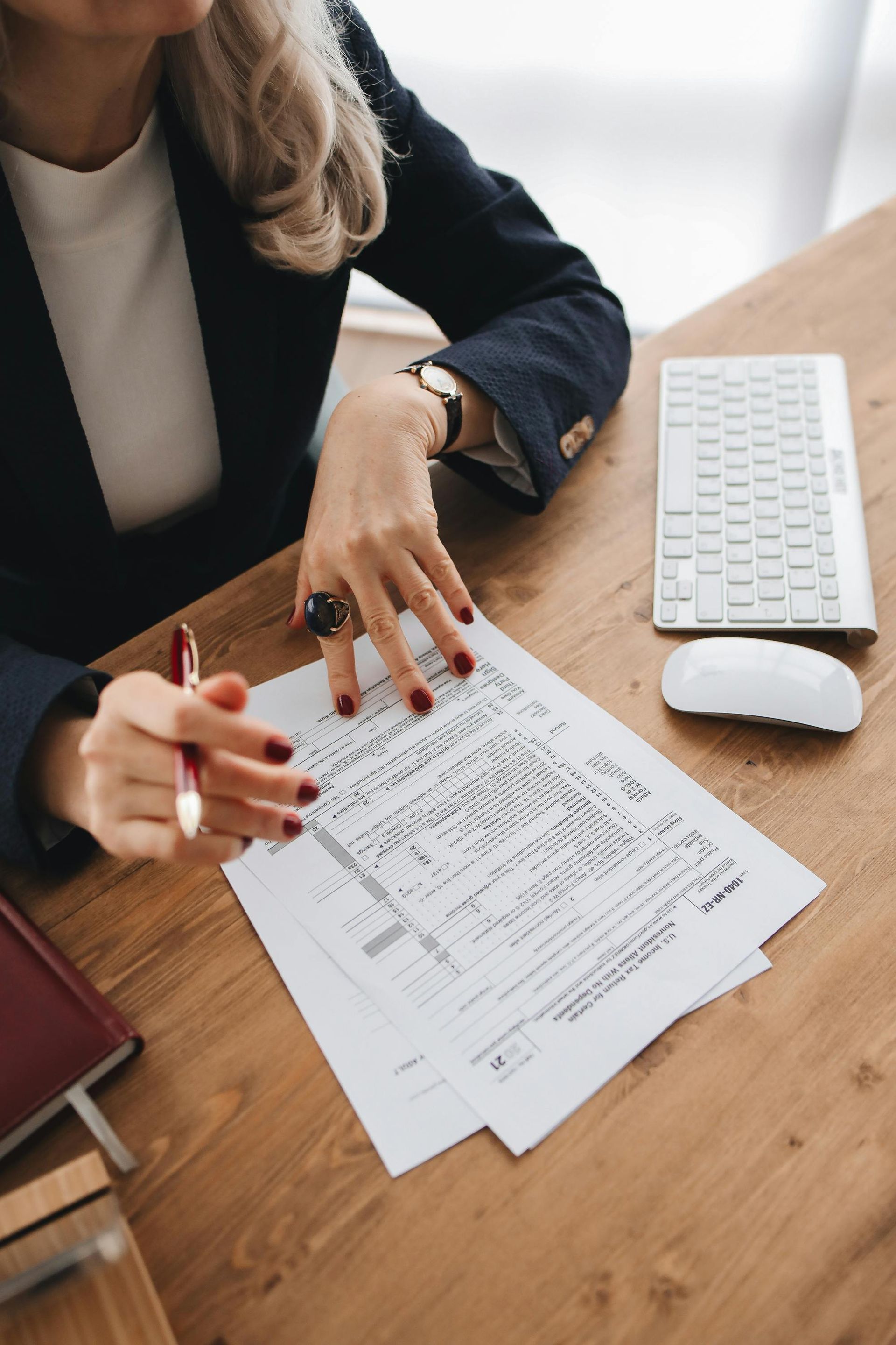 Person reviewing printed documents at a wooden desk beside a keyboard and mouse