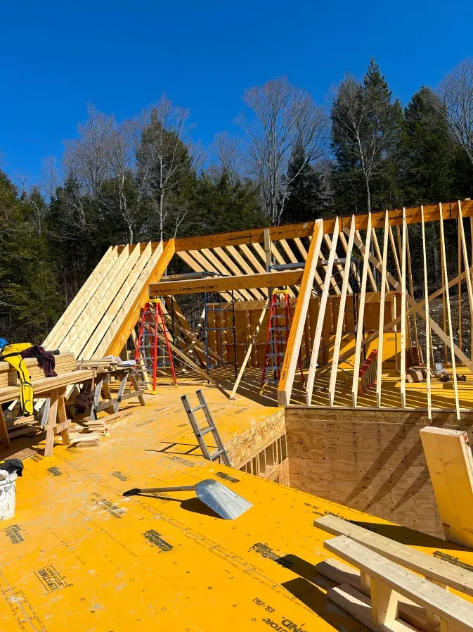 Construction site with wooden roof framing on a yellow platform under a clear blue sky