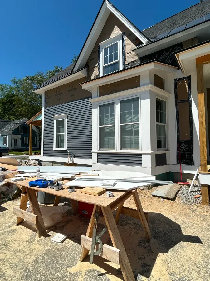 House exterior under construction with white trim, blue siding, and sawhorses in the foreground