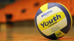 Yellow, blue, and white Mikasa youth volleyball on a court floor with a blurred orange background