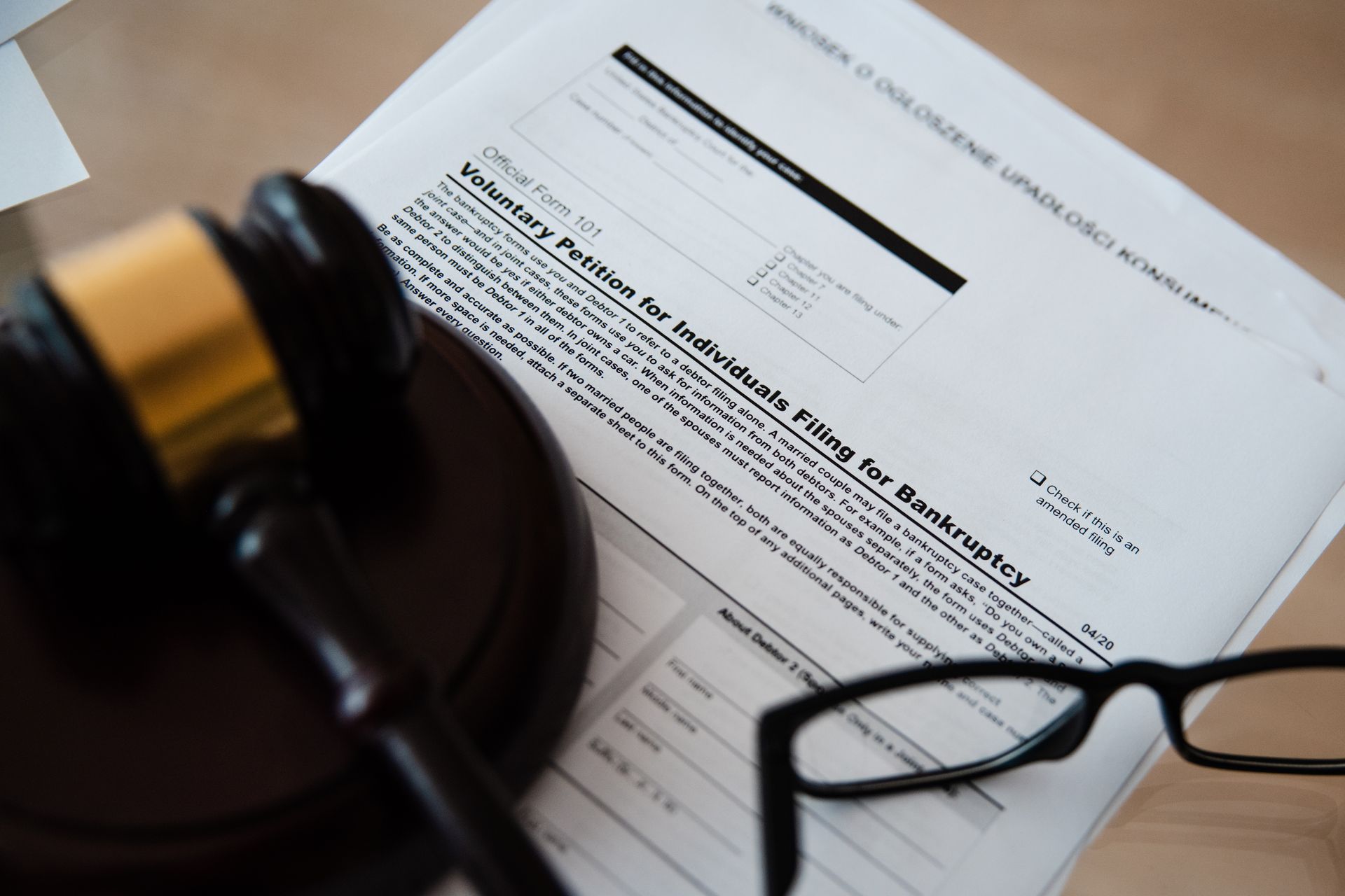 Wooden gavel and reading glasses on a voluntary petition for individuals filing for bankruptcy form