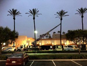 Palm trees and building at dusk with a cherry car and construction crane in the parking lot.