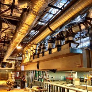 Construction site with exposed HVAC ductwork and a partially built structure; workers visible.