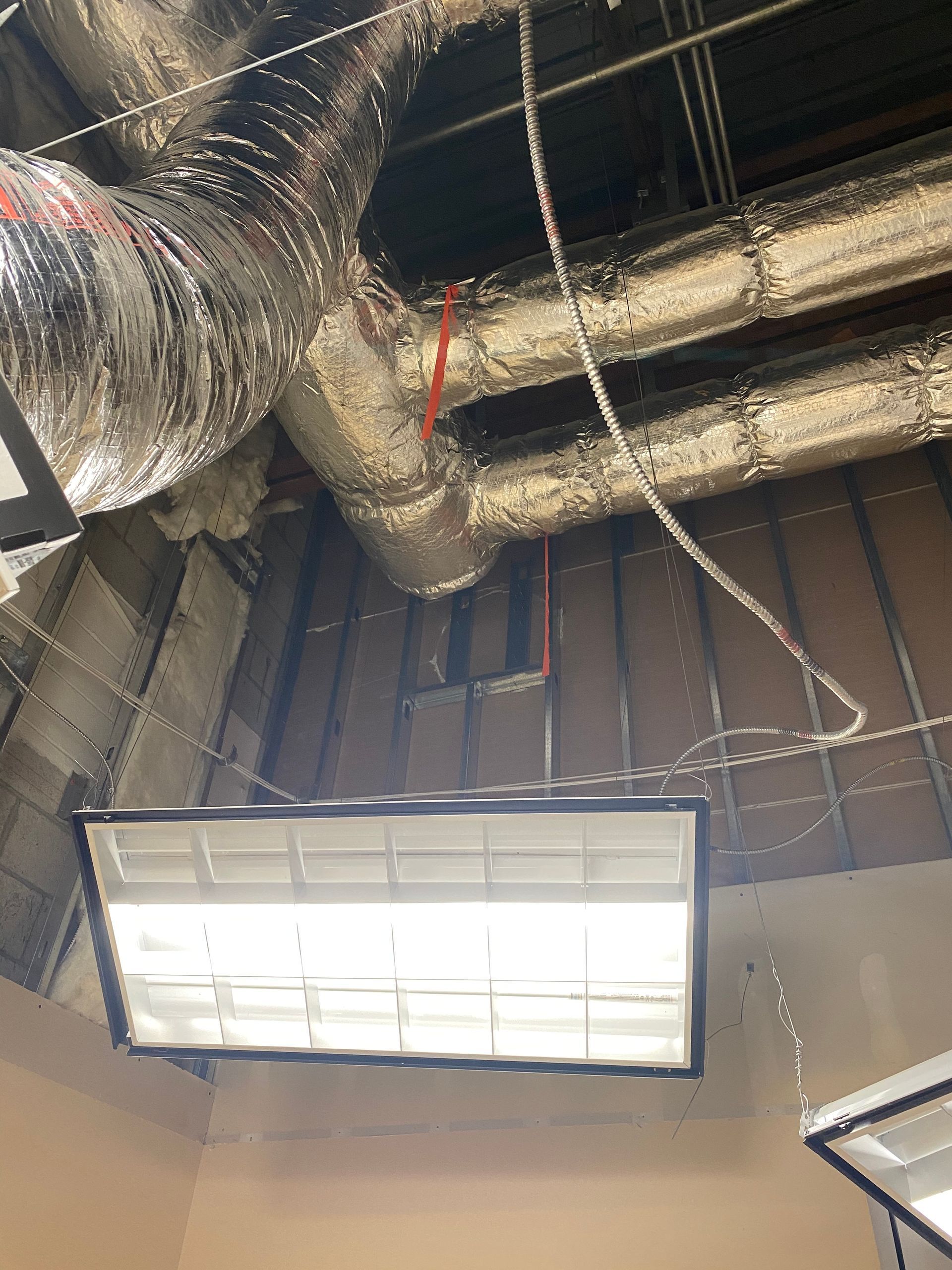 Ceiling view of HVAC ductwork and fluorescent light fixtures.