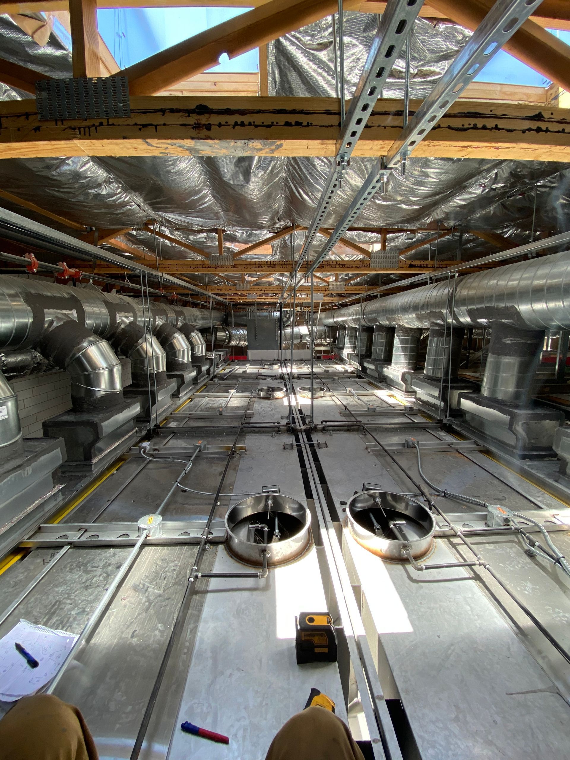 Interior view of a building's unfinished ceiling with ductwork, insulation, and metal framework.