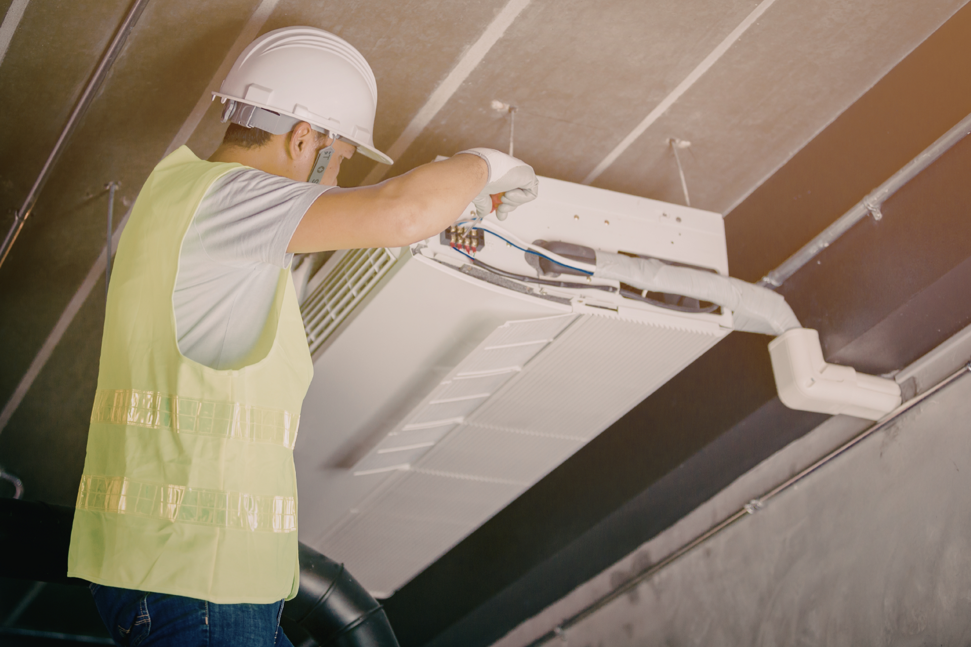HVAC unit installed in a wooden attic framework, with silver insulated ductwork running through the beams.