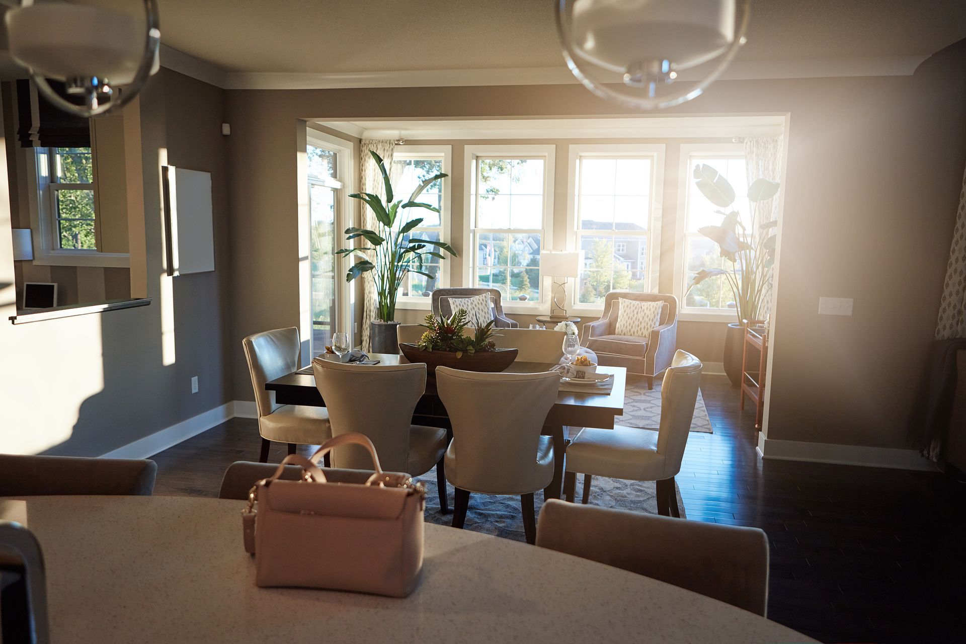 Dining room with table, chairs, handbag, and windows with sunlight streaming in.