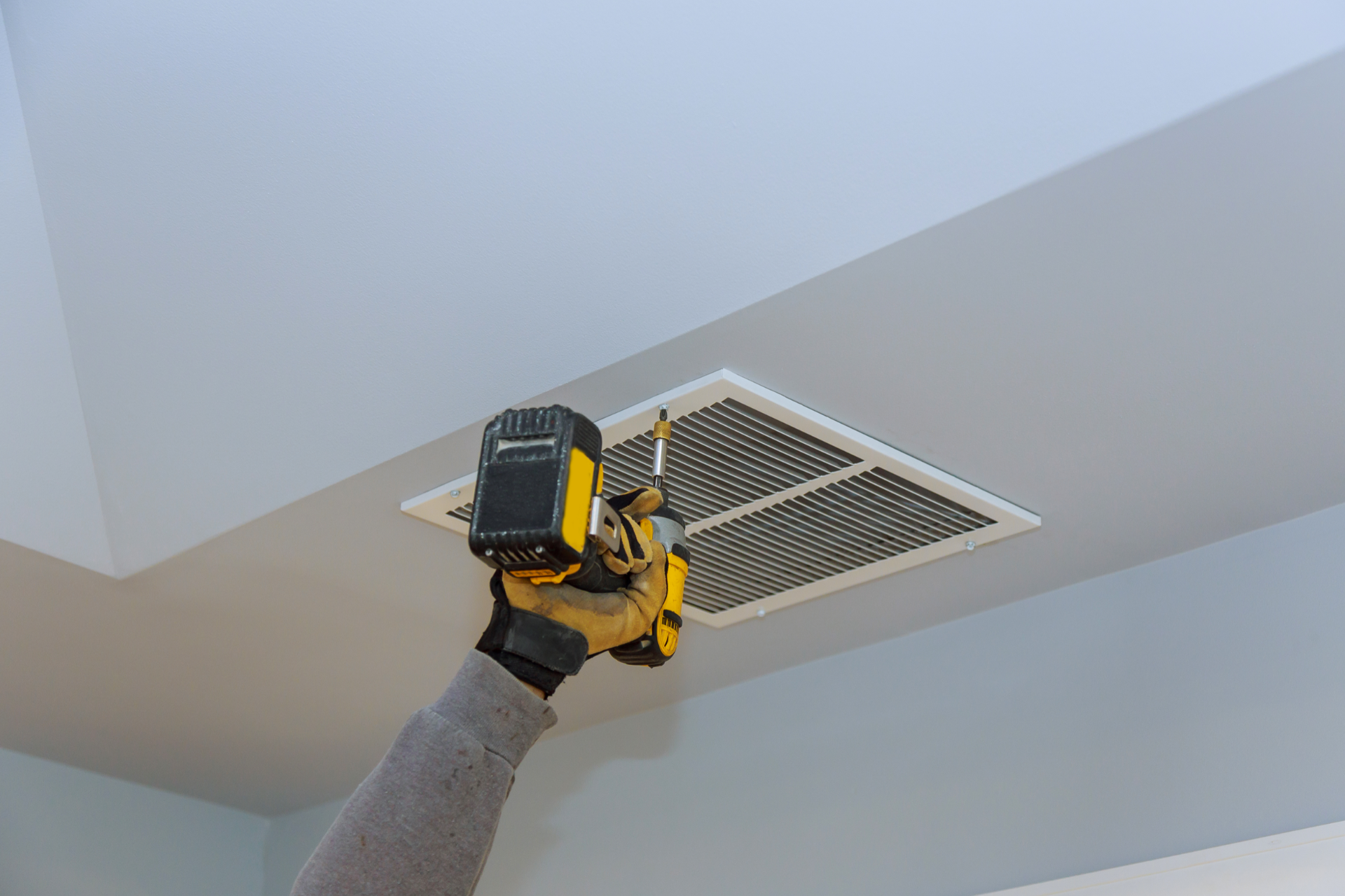 HVAC unit installed in a wooden attic framework with silver insulated ductwork.