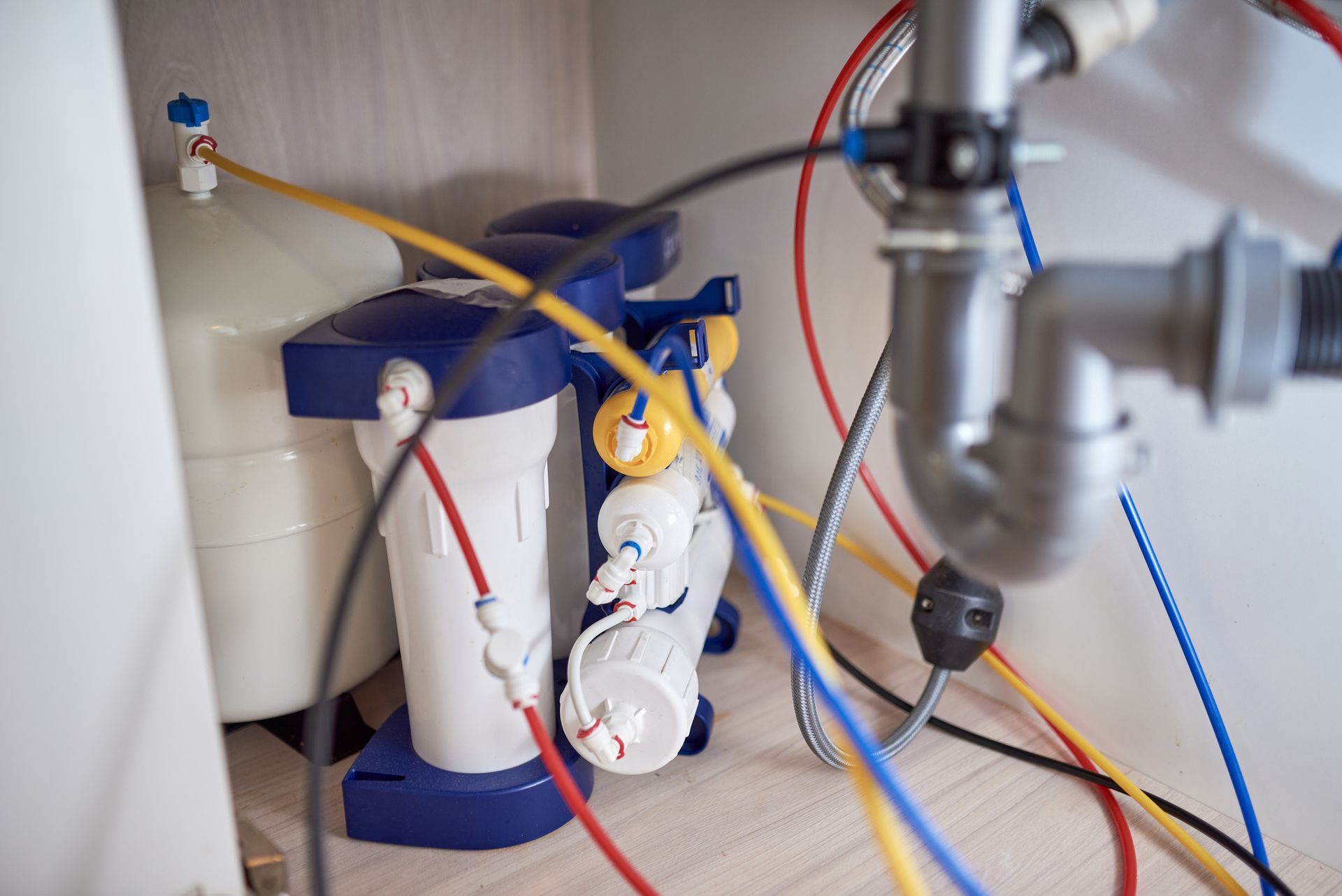A water filter is sitting under a sink in a kitchen.