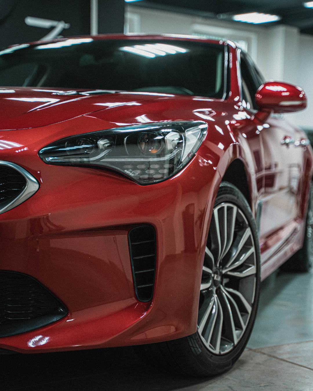 Red Kia Stinger car parked, with focus on front, and black grill.