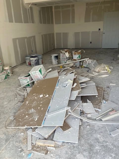 Construction debris and drywall scraps piled on the floor in an unfinished room under renovation