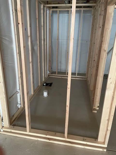 Partially framed interior room with fresh concrete floor and window at the far end