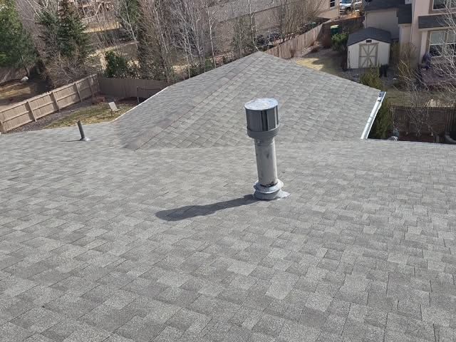 Rooftop with gray shingles and a vent pipe, viewed from above