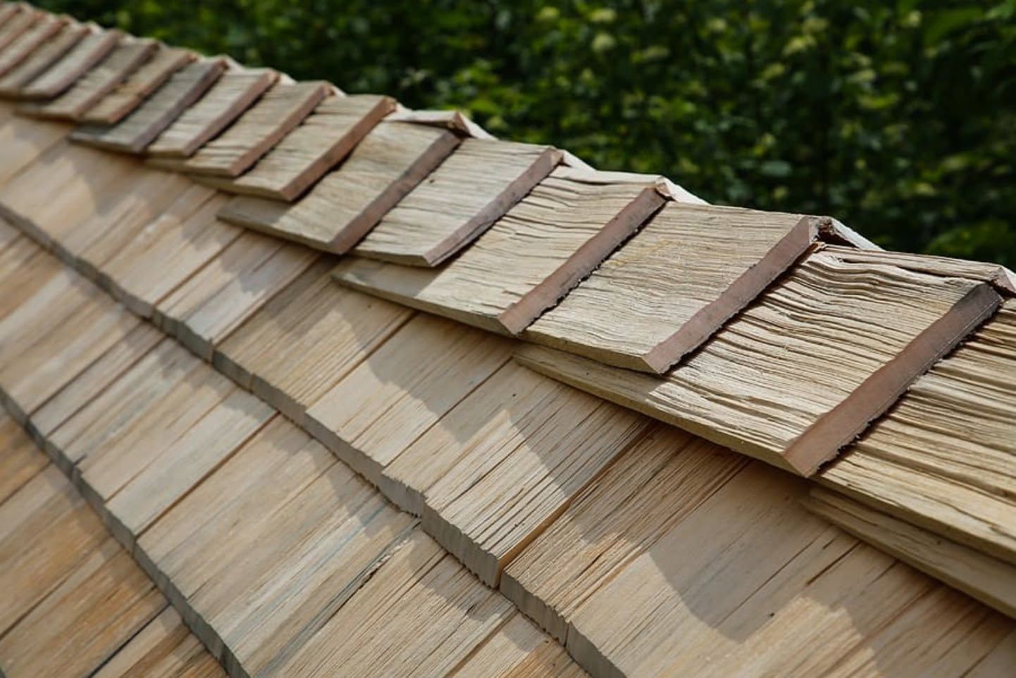 Close-up of a sloped shingle roof with overlapping weathered tan and brown tiles