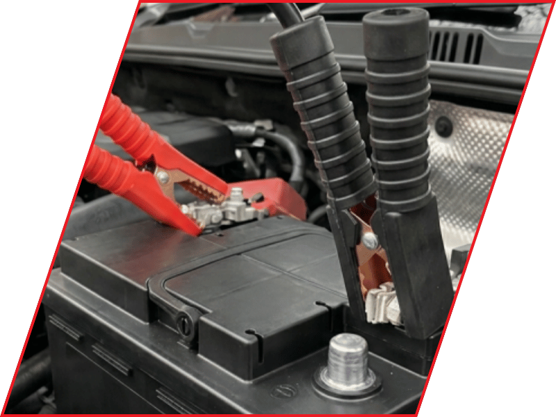 Close-up of jumper cable clamps connected to a vehicle battery in the engine compartment