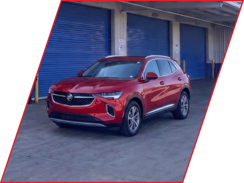 Red Buick Envision SUV parked outside an automotive service facility with blue garage doors