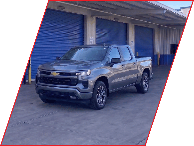 Gray Chevrolet Silverado pickup truck parked outside an automotive service facility with blue garage doors
