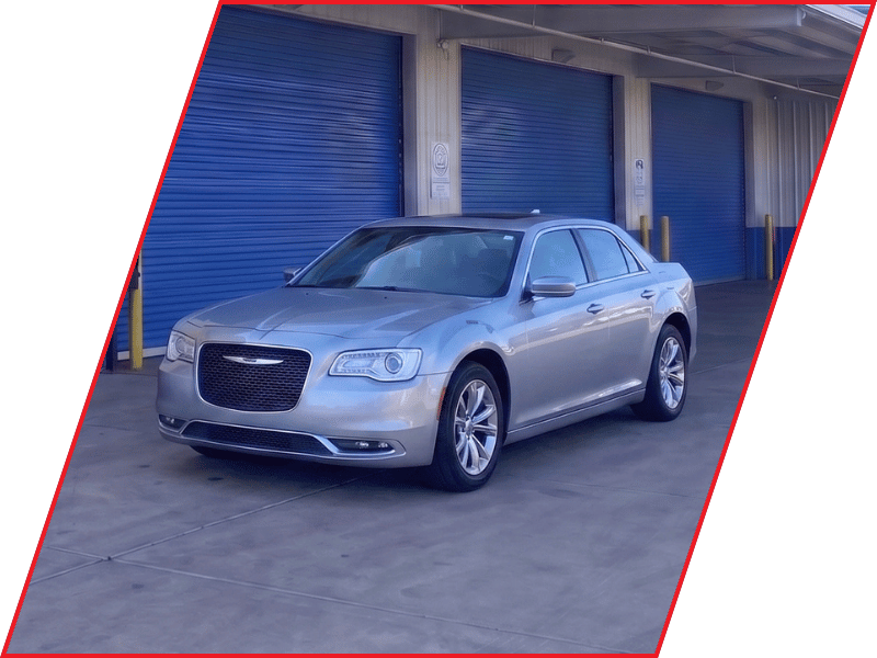 Silver Chrysler 300 sedan parked outside an automotive service facility with blue garage doors