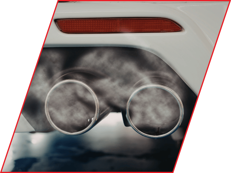 Close-up of dual vehicle exhaust pipes releasing visible exhaust vapor