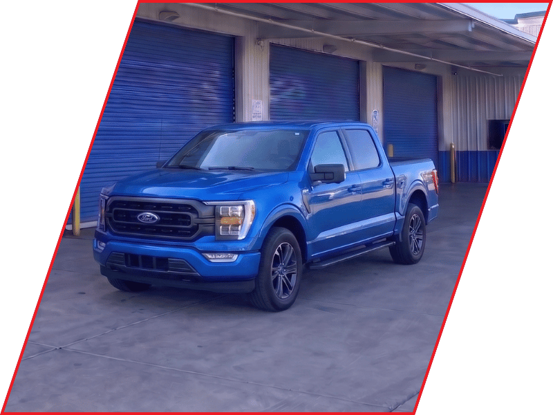 Blue Ford F-150 pickup truck parked outside an automotive service facility with blue garage doors