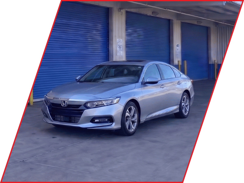 Silver Honda Accord sedan parked outside an automotive service facility with blue garage doors