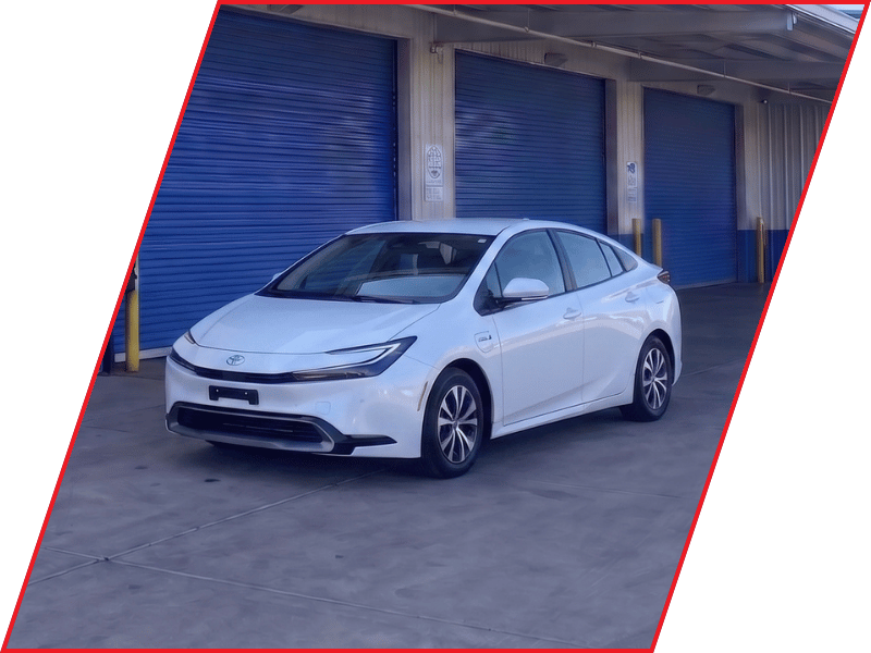 White Toyota Prius hybrid parked outside an automotive service facility with blue garage doors