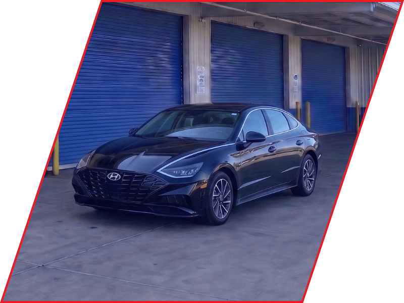 Black Hyundai Sonata sedan parked outside an automotive service facility with blue garage doors