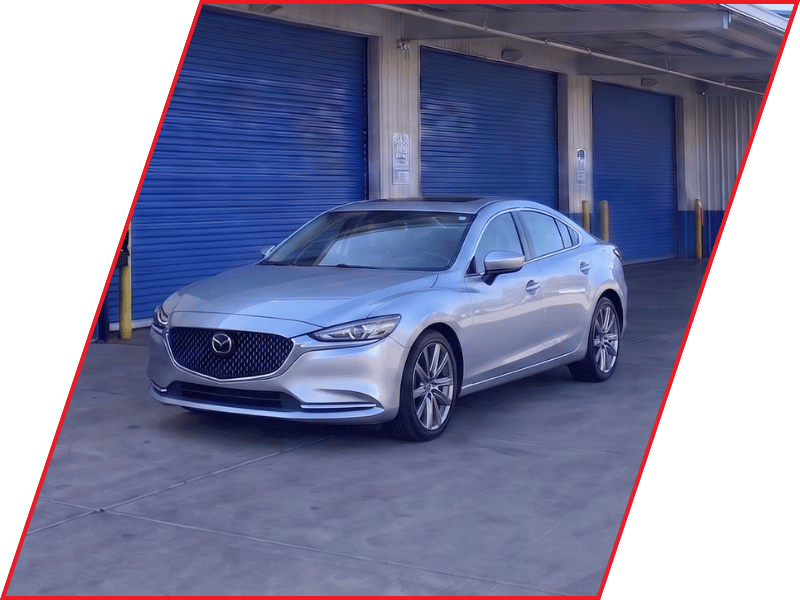 Silver Mazda6 sedan parked outside an automotive service facility with blue garage doors