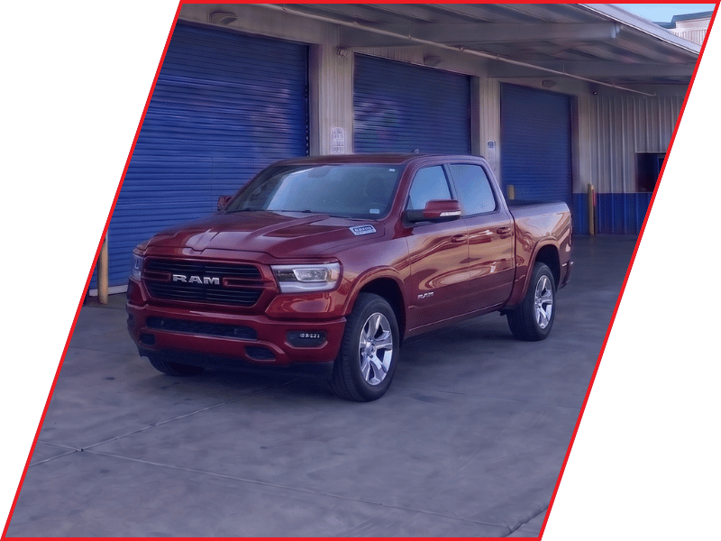 Red RAM 1500 pickup truck parked outside an automotive service facility with blue garage doors