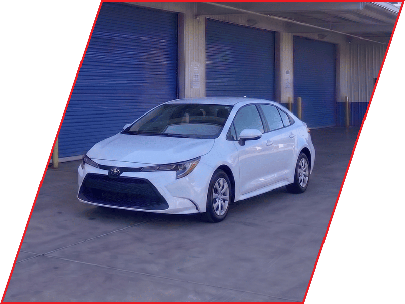 White Toyota Corolla sedan parked outside an automotive service facility with blue garage doors