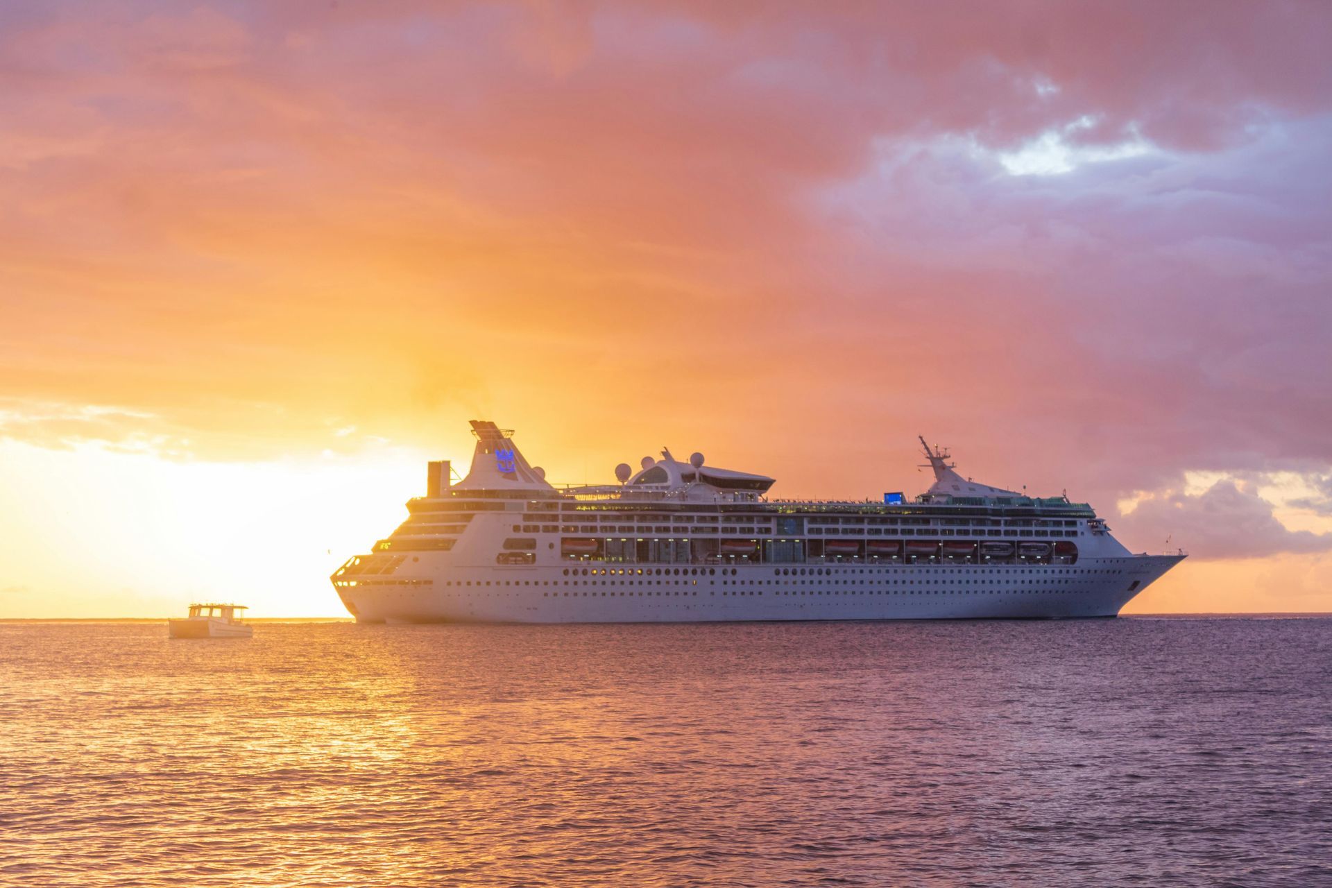 Cruise ship at sea during a colorful orange-pink sunset