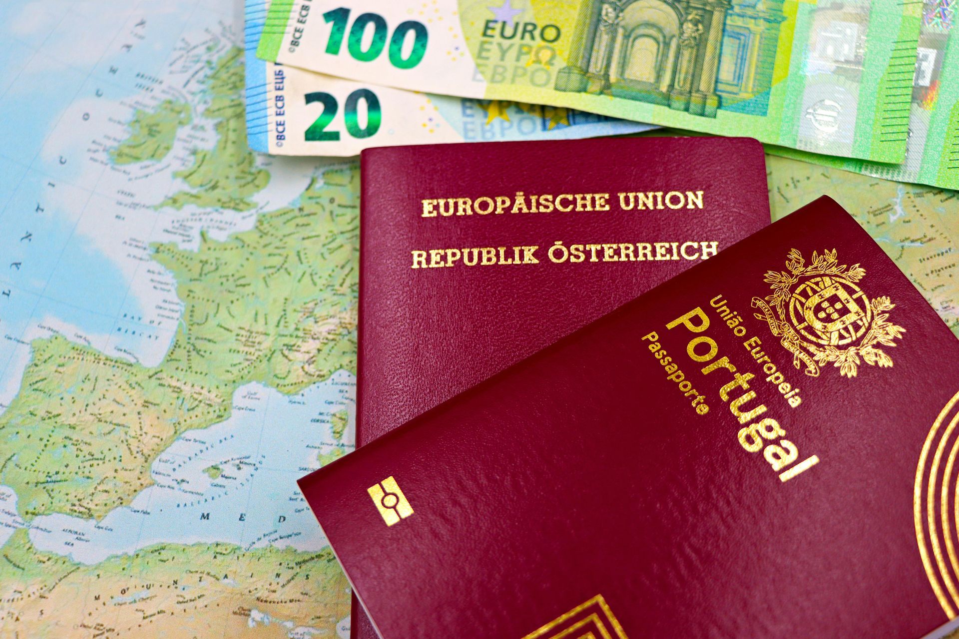 Two passports (Austria and Portugal) with Euro banknotes on a map.