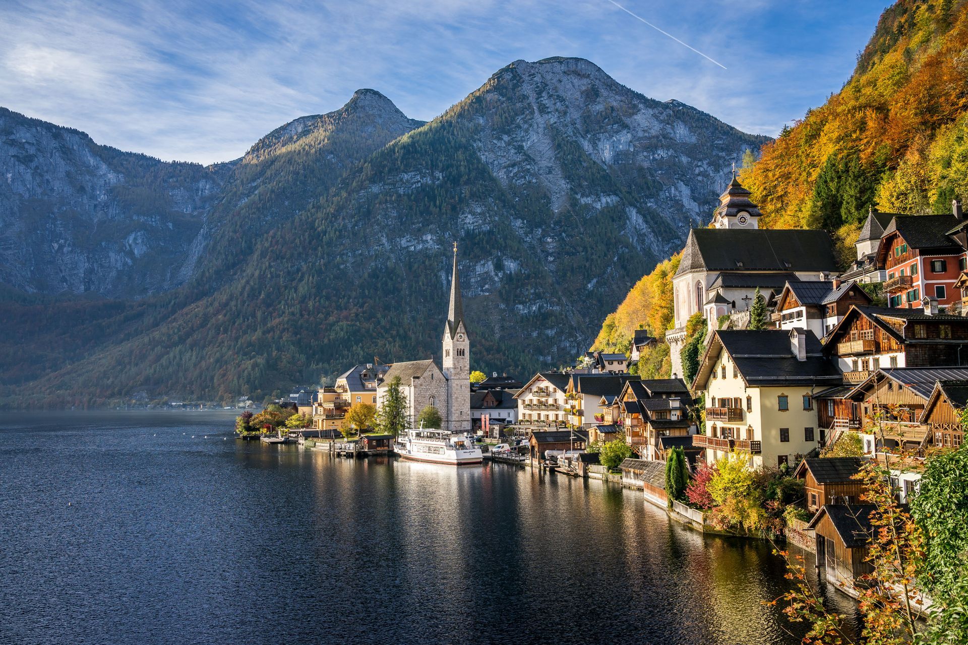 Lakeside Alpine village with church tower and colorful houses beside a calm mountain lake