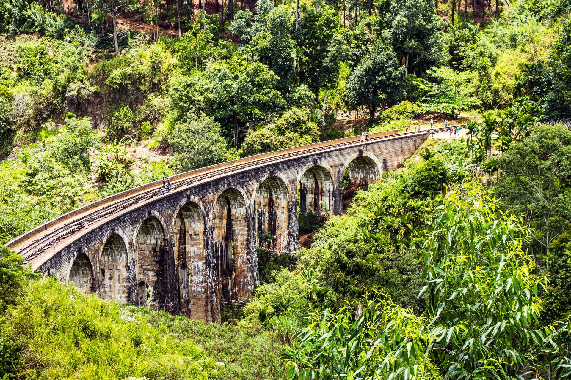 Nine Arch Bridge in Sri Lanka, a stone arch railway bridge surrounded by lush green trees.