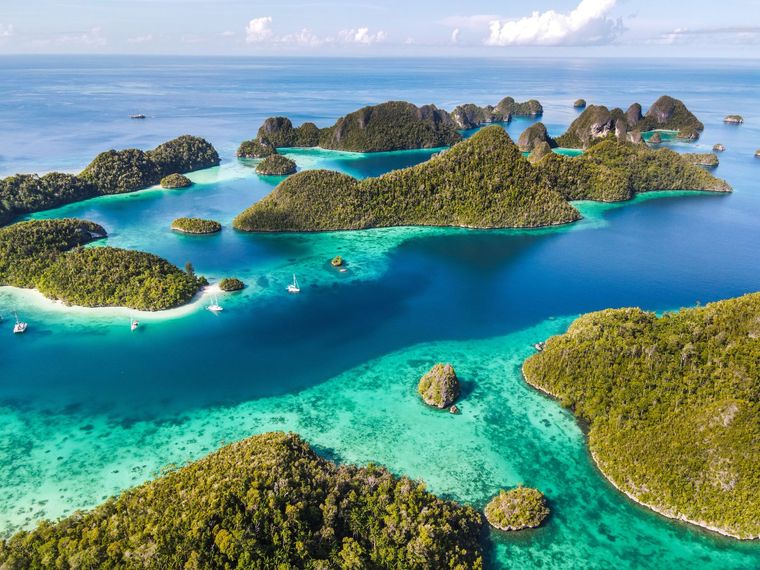 Tropical islands with green foliage surrounded by turquoise and blue water.