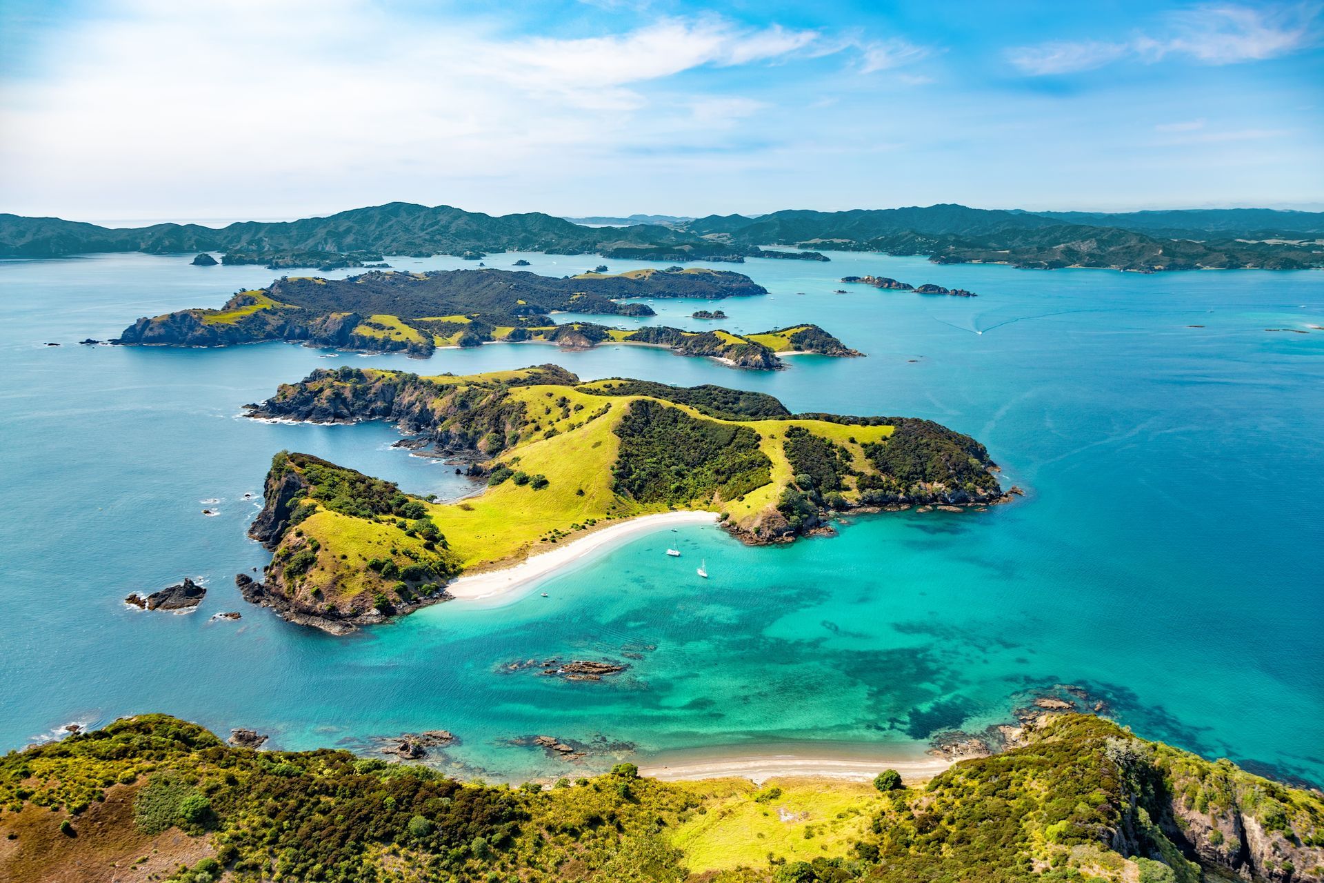 Aerial view of lush green islands surrounded by turquoise water and blue sky.