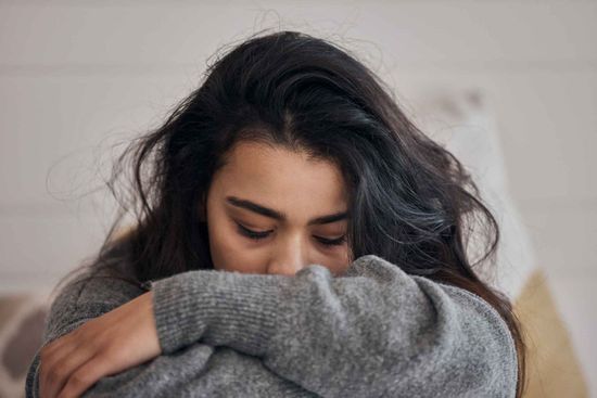 A Woman Is Covering Her Face With Her Sweater While Sitting On A Couch – Independence, MO - Mary Hargrave
