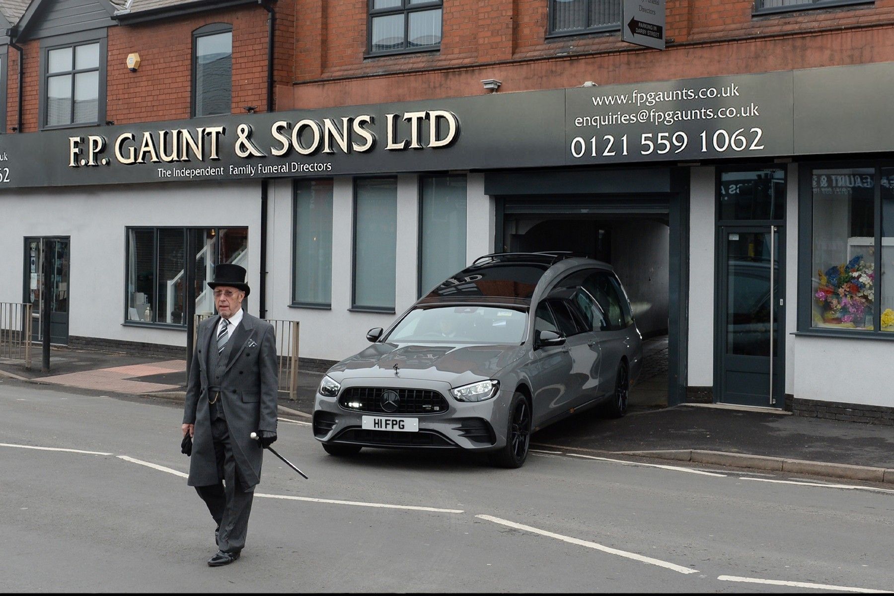 funeral director walking in front of the hearse