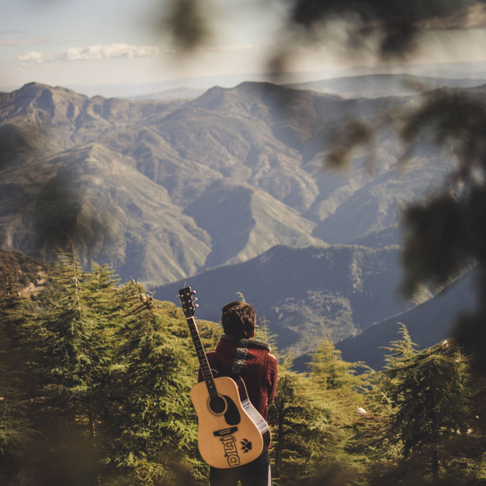 man with a guitar in front of mountains