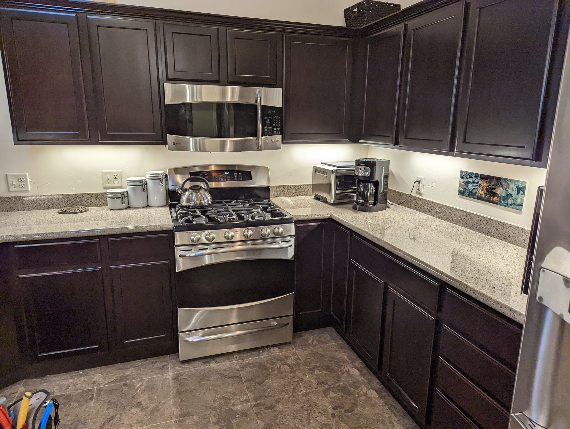 A kitchen with stainless steel appliances and dark cabinets