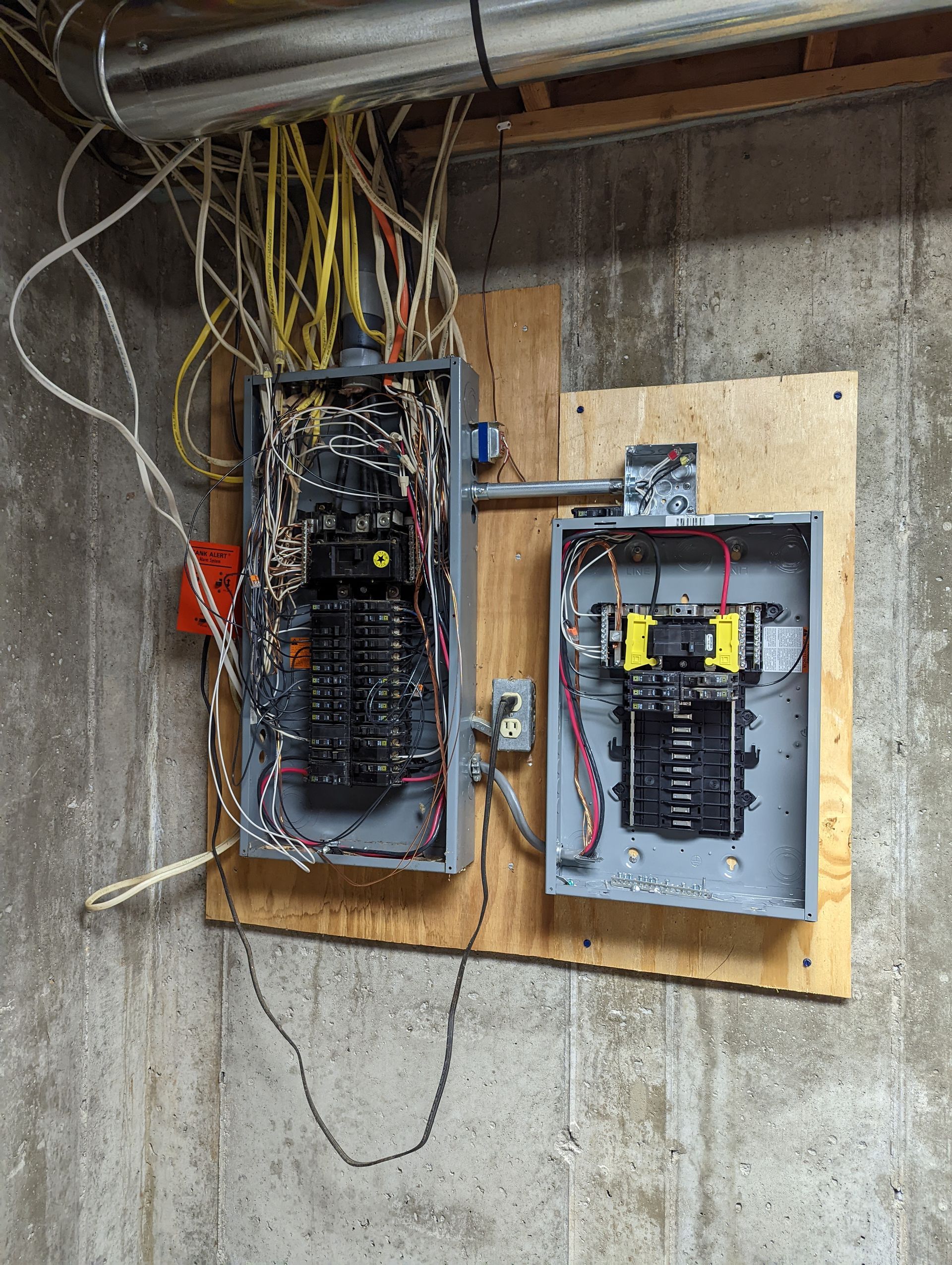 Two electrical boxes are hanging on a wall with wires coming out of them