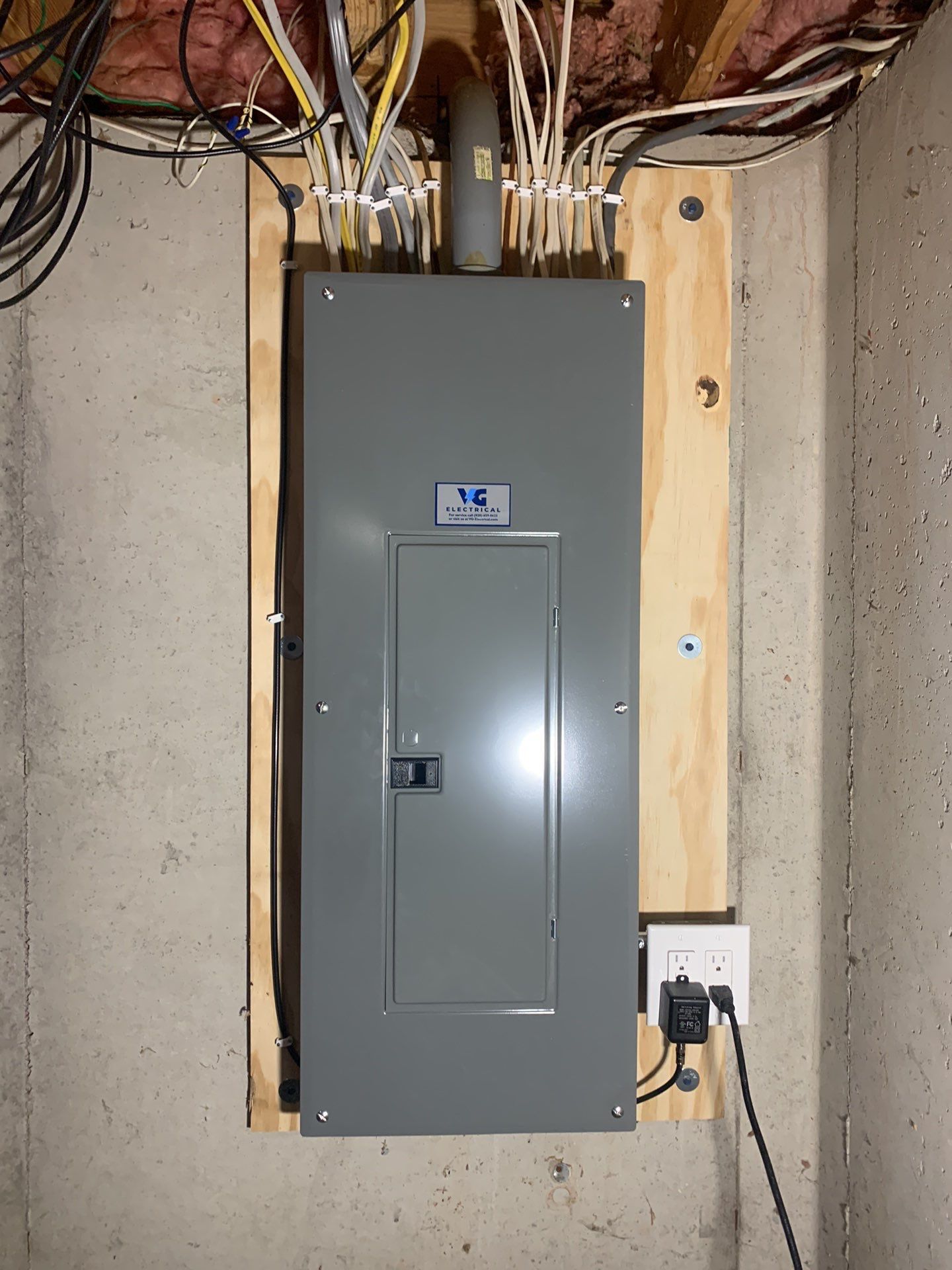 A gray electrical box is mounted on a wooden frame