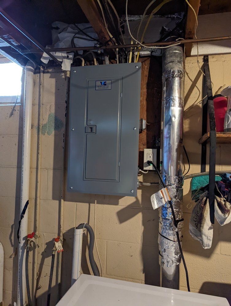 A utility box is hanging from the ceiling in a basement.