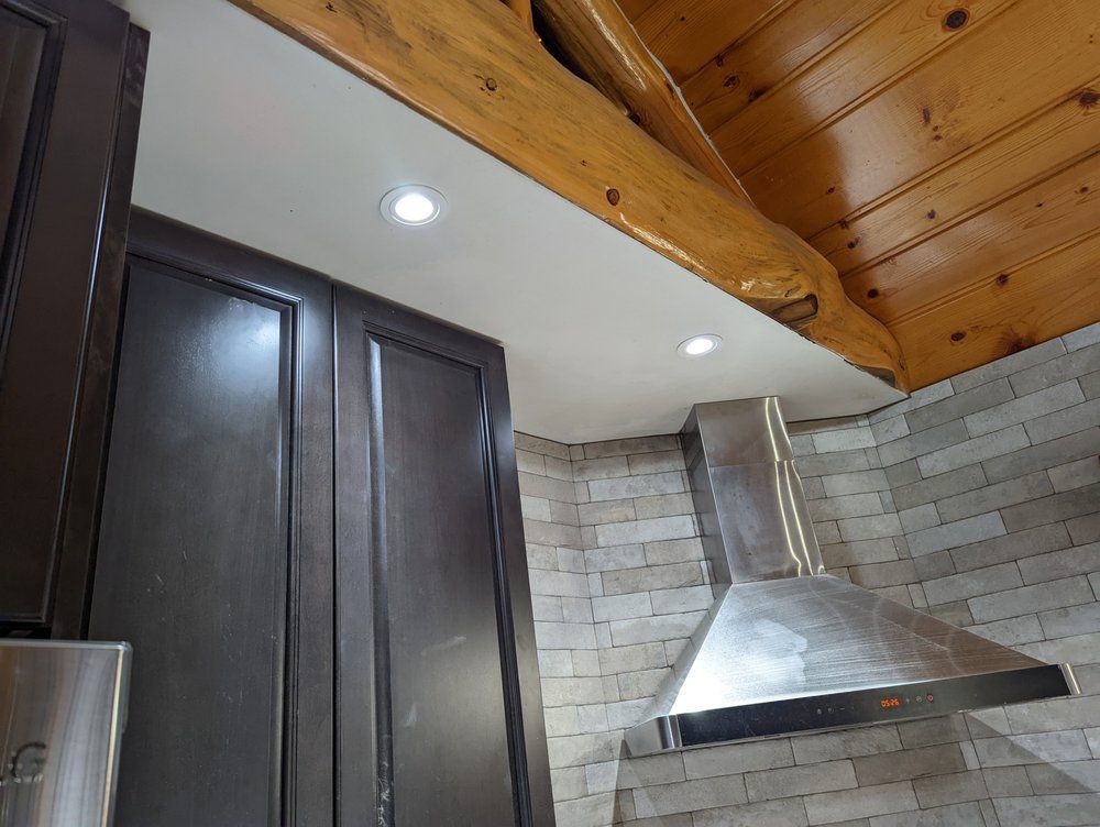 A kitchen with a wooden ceiling and a stainless steel hood.