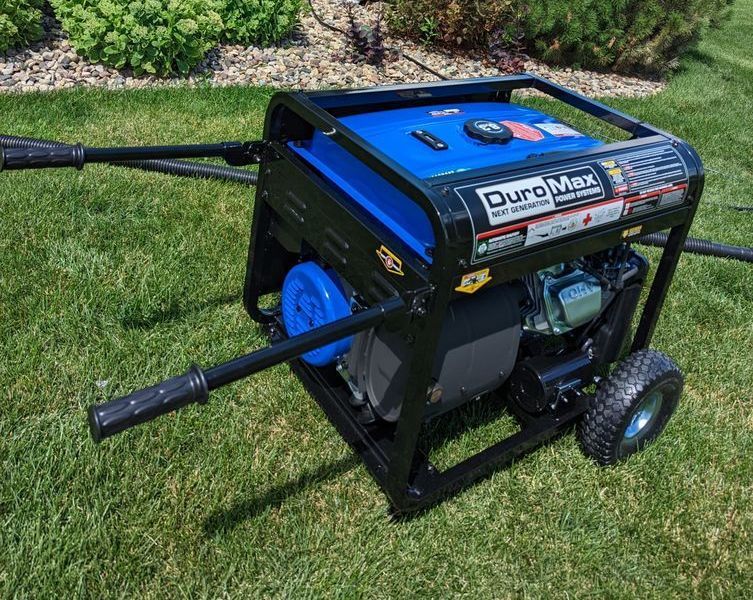A portable generator is sitting on top of a lush green lawn.