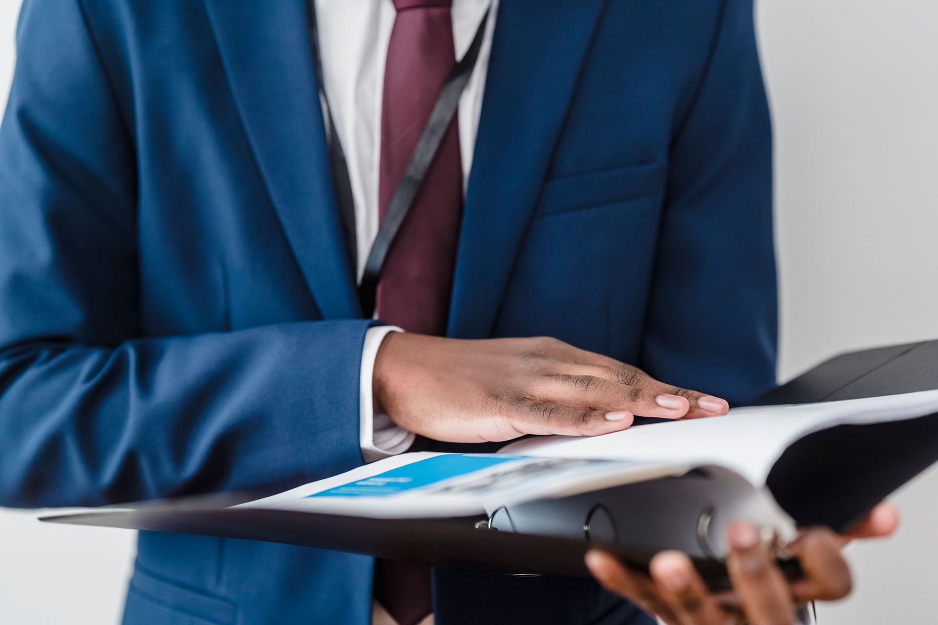 Person in a blue suit signing a document on a clipboard.