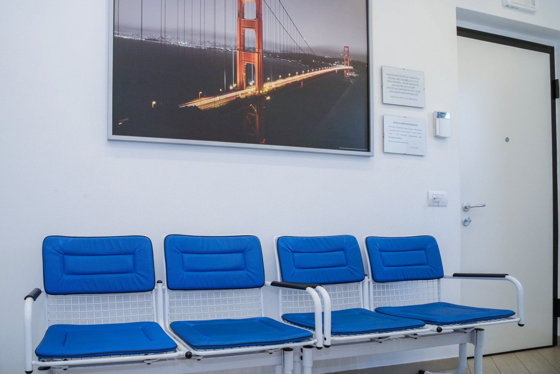Sedie blu in una sala d'attesa sotto una foto appesa al muro del Golden Gate Bridge.