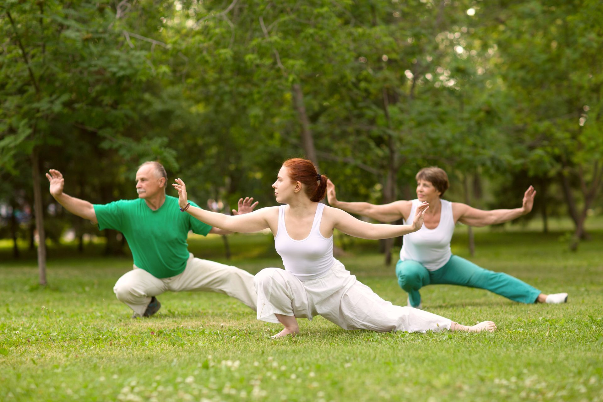 three people doing tai chi in a park