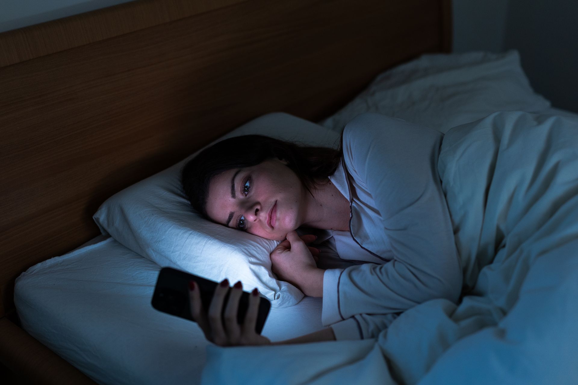 woman lying in bed on her phone late at night